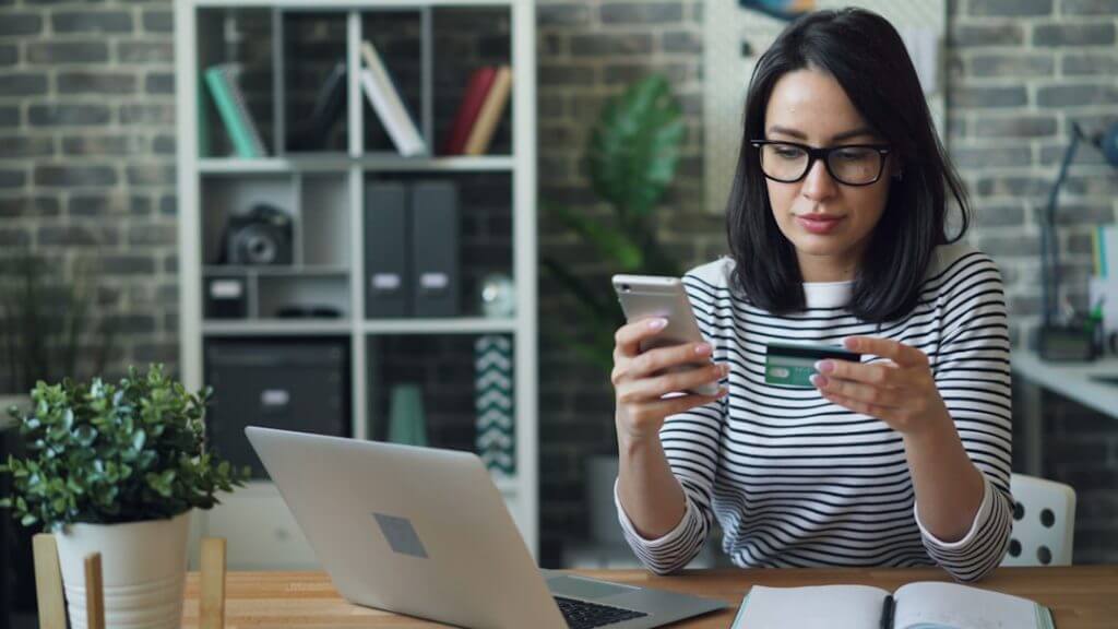 a-woman-sitting-at-a-table-looking-at-her-cell-phone-1jnn9qhmtgu-1024x576